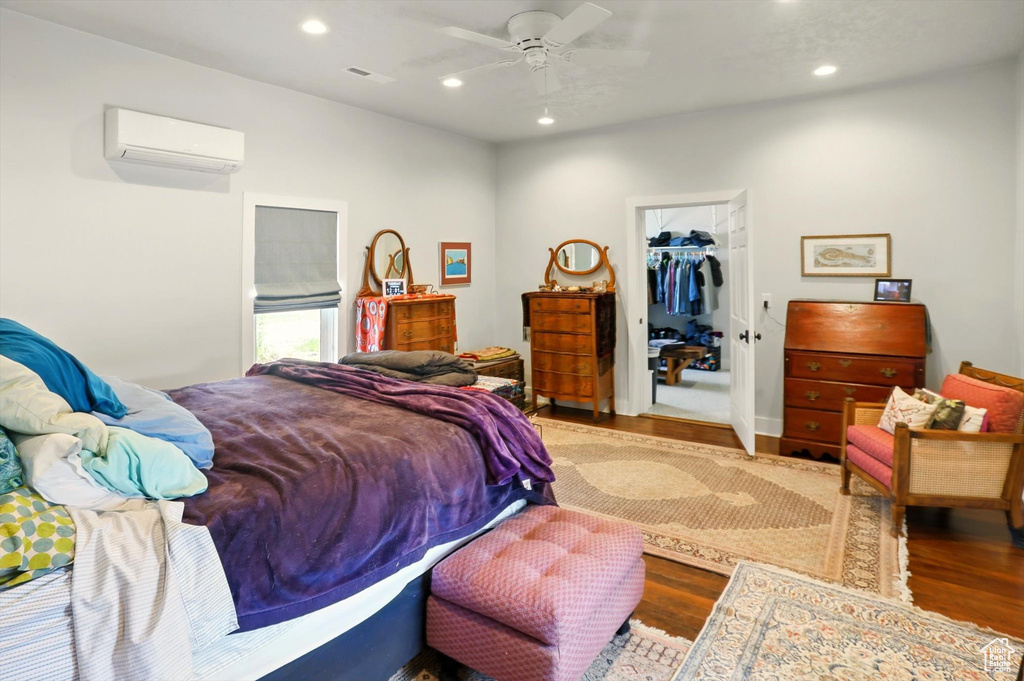 Bedroom featuring a wall mounted air conditioner, wood finished floors, recessed lighting, a walk in closet, and a closet