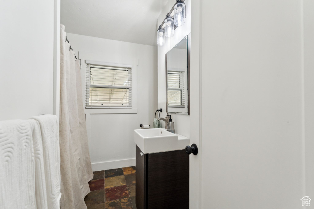 Bathroom with vanity, baseboards, and stone finish floors