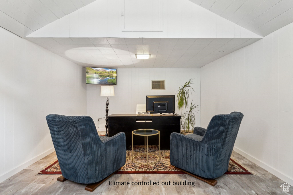 Sitting room with wood finished floors, lofted ceiling, baseboards, and a desk