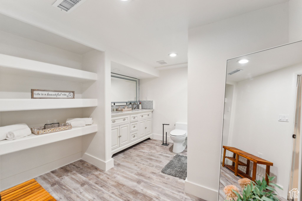 Bathroom with vanity, wood finished floors, toilet, recessed lighting, and baseboards