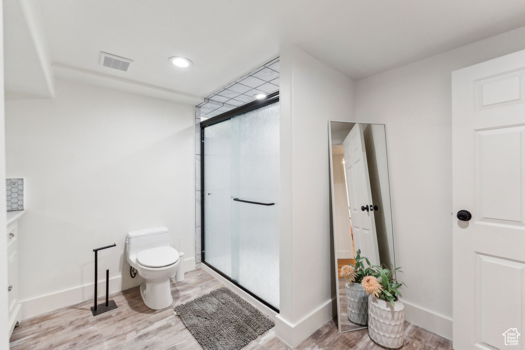 Full bathroom featuring toilet, wood finished floors, a stall shower, baseboards, and recessed lighting