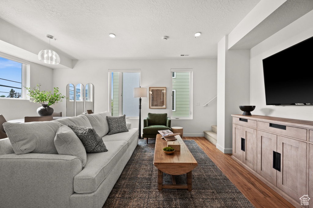 Living room with dark wood-type flooring, stairs, a textured ceiling, recessed lighting, and baseboards