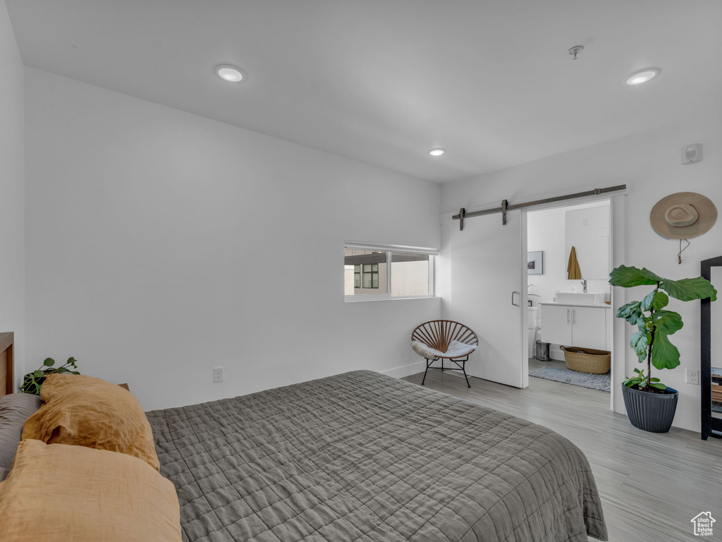 Bedroom featuring a barn door, recessed lighting, and wood finished floors