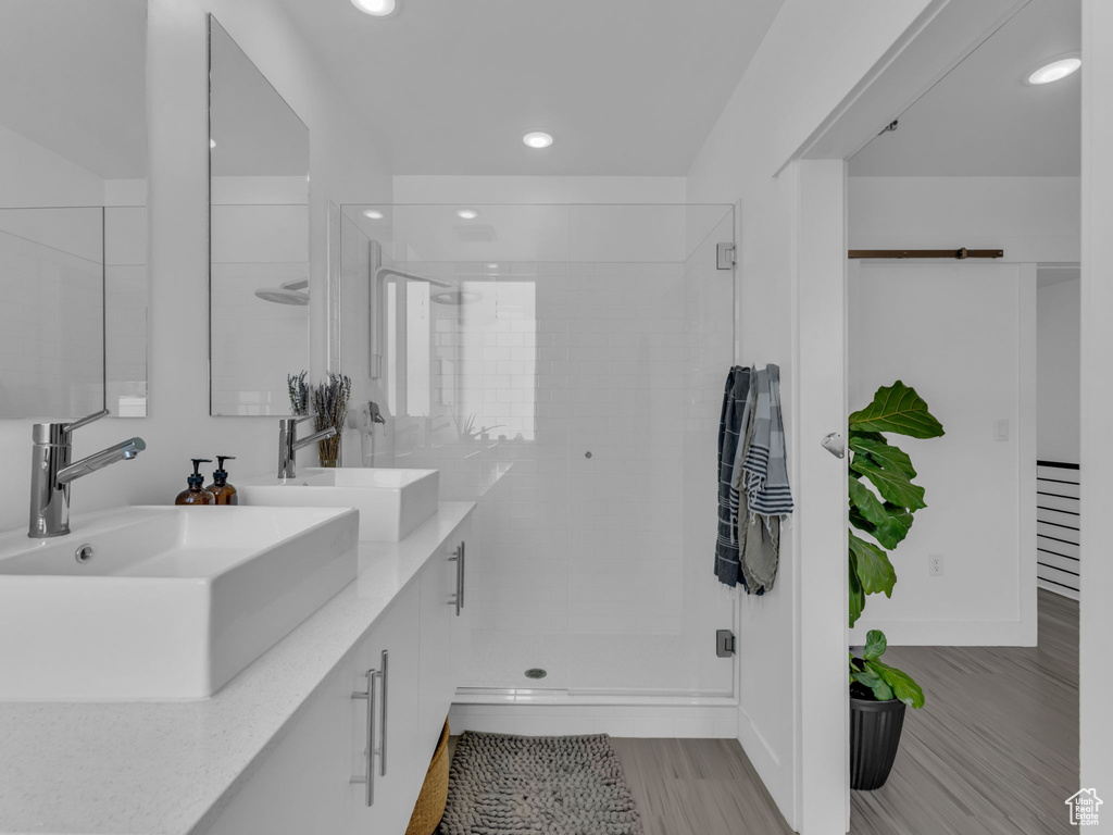 Bathroom with double vanity, recessed lighting, a stall shower, and wood finished floors
