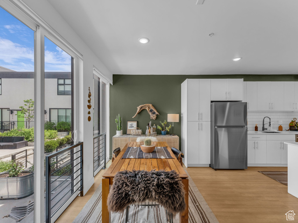 Kitchen with freestanding refrigerator, a sink, light countertops, tasteful backsplash, and light wood-style floors