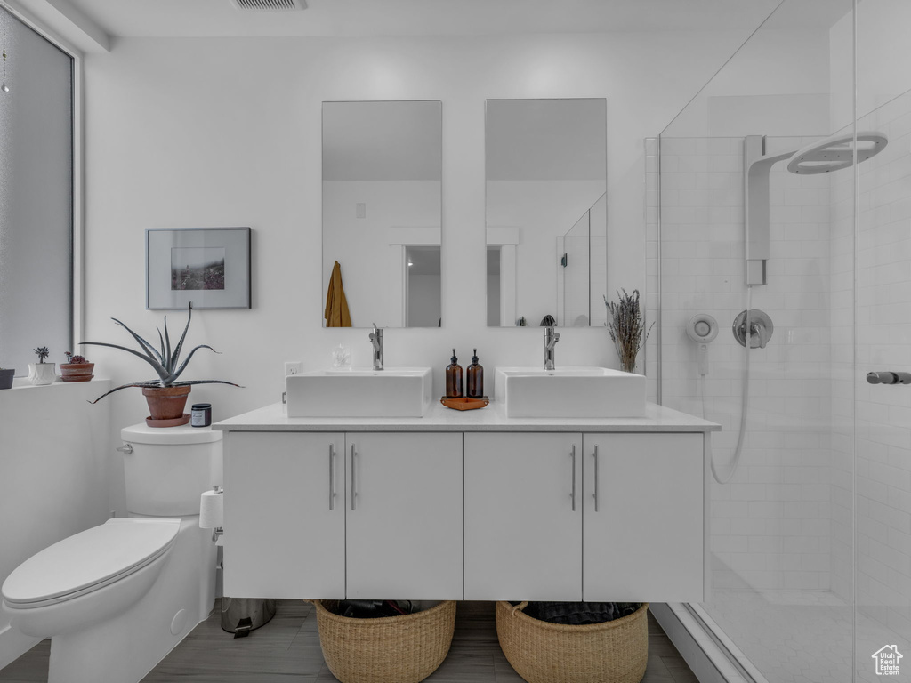 Bathroom featuring double vanity, toilet, and a shower stall