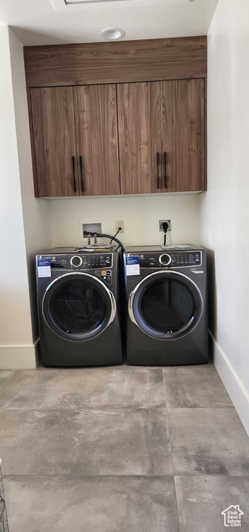 Washroom featuring baseboards, washer and clothes dryer, and cabinet space