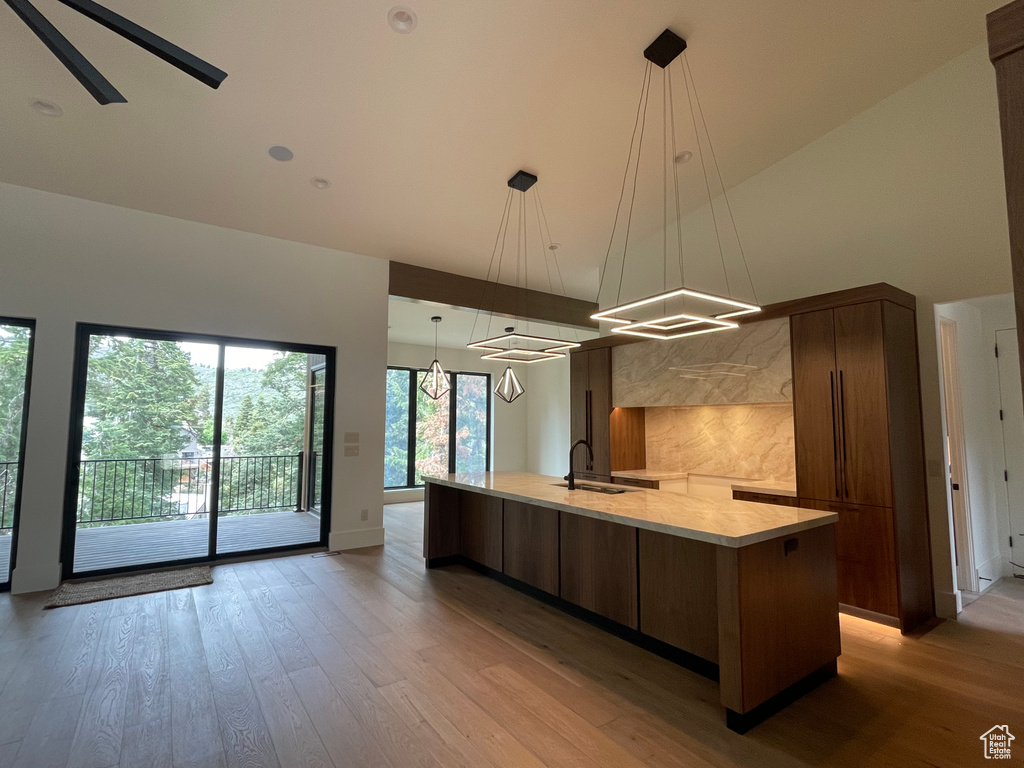 Kitchen with modern cabinets, high vaulted ceiling, a large island, light wood-type flooring, and a sink