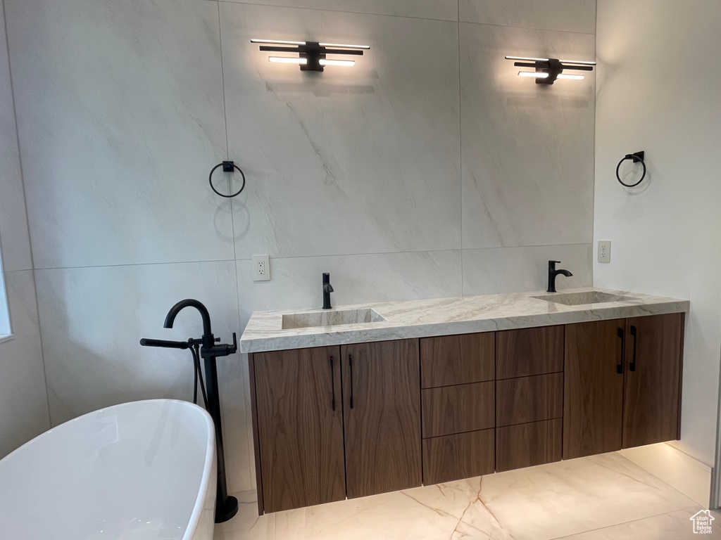 Bathroom featuring double vanity, a freestanding tub, and tile walls