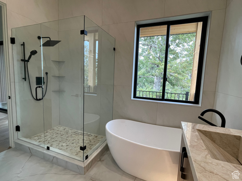 Full bath with a freestanding bath, a shower stall, healthy amount of natural light, and tile walls