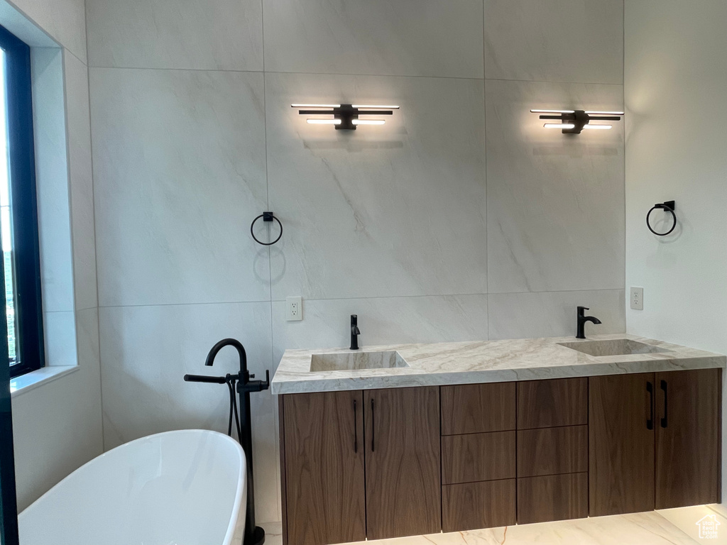 Full bath featuring a freestanding bath, double vanity, and tile walls