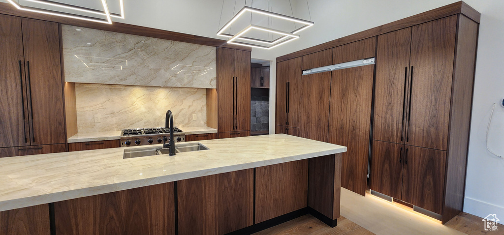Kitchen featuring decorative backsplash, a sink, and wood finished floors