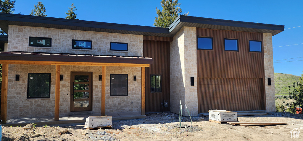 View of front facade with a standing seam roof, stone siding, and metal roof