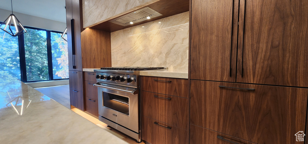 Kitchen featuring high end stainless steel range oven, modern cabinets, light countertops, and premium range hood