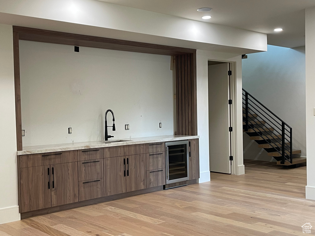 Indoor bar with beverage cooler, light wood-style floors, stairway, baseboards, and recessed lighting