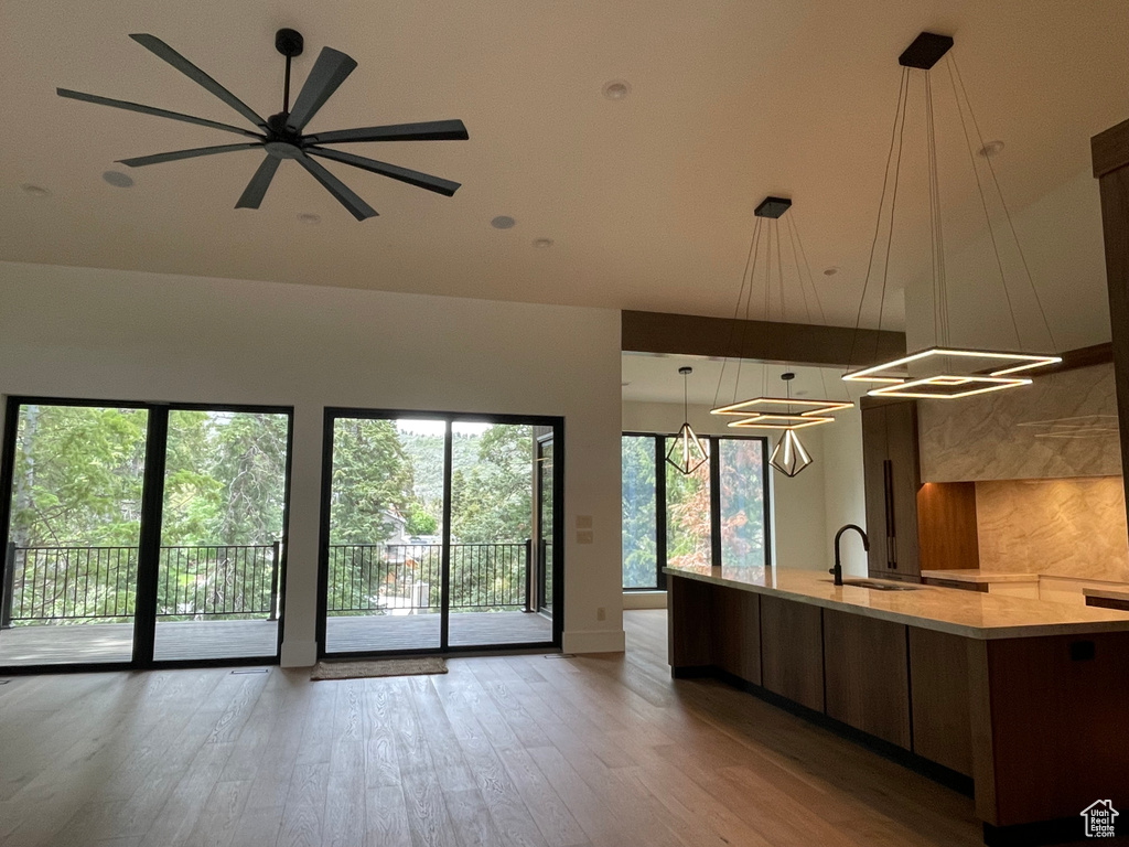 Kitchen featuring open floor plan, a sink, wood finished floors, modern cabinets, and a large island with sink