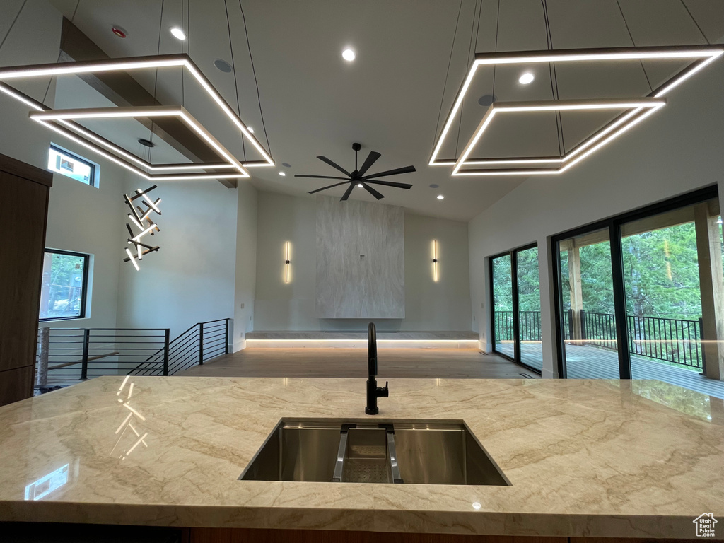 Kitchen featuring a sink, recessed lighting, open floor plan, light stone counters, and a towering ceiling