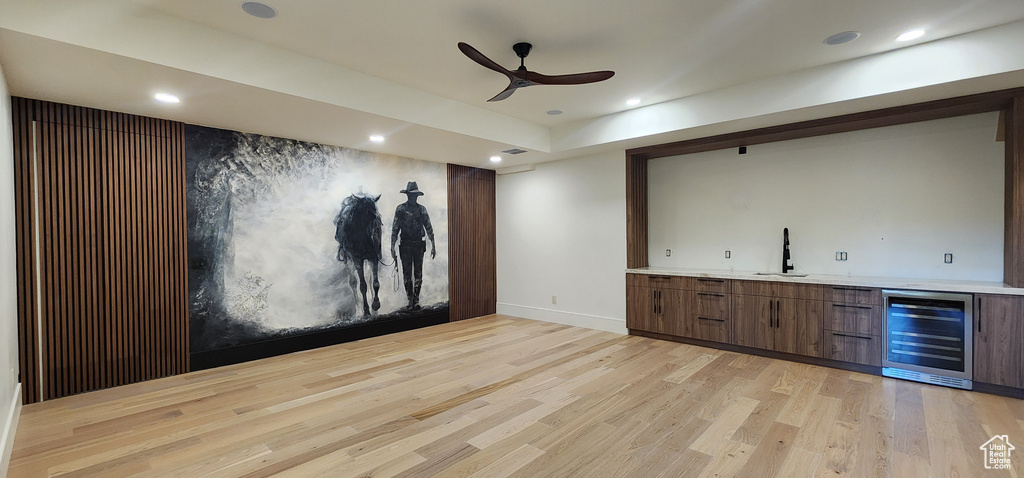 Indoor wet bar featuring beverage cooler, light wood-style floors, a ceiling fan, baseboards, and recessed lighting