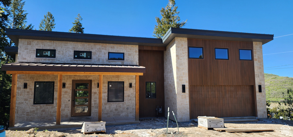 View of front of property featuring a standing seam roof, metal roof, and a garage
