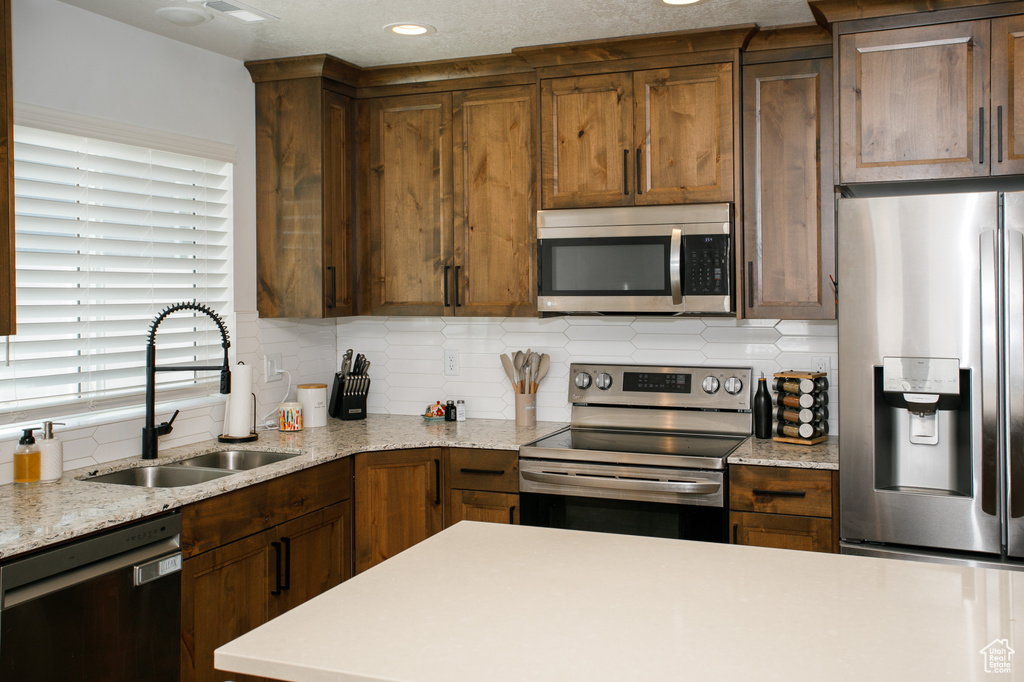 Kitchen featuring appliances with stainless steel finishes, a sink, backsplash, and recessed lighting