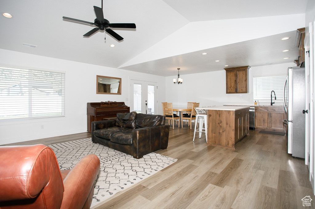 Living room with lofted ceiling, a chandelier, light wood-style floors, ceiling fan, and recessed lighting
