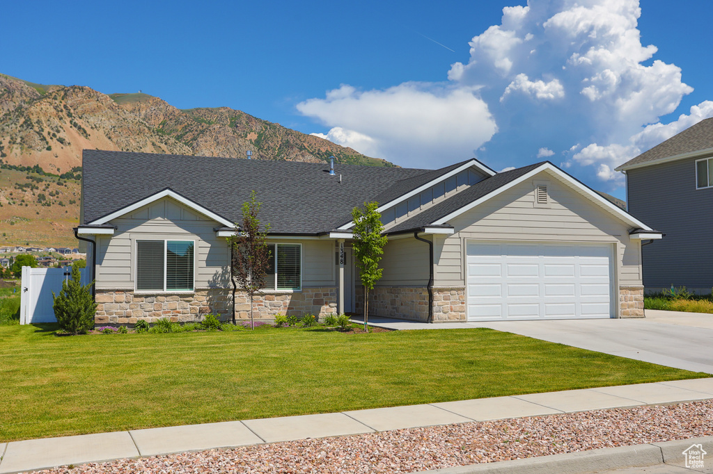 View of front of home featuring stone siding, an attached garage, a shingled roof, and concrete driveway