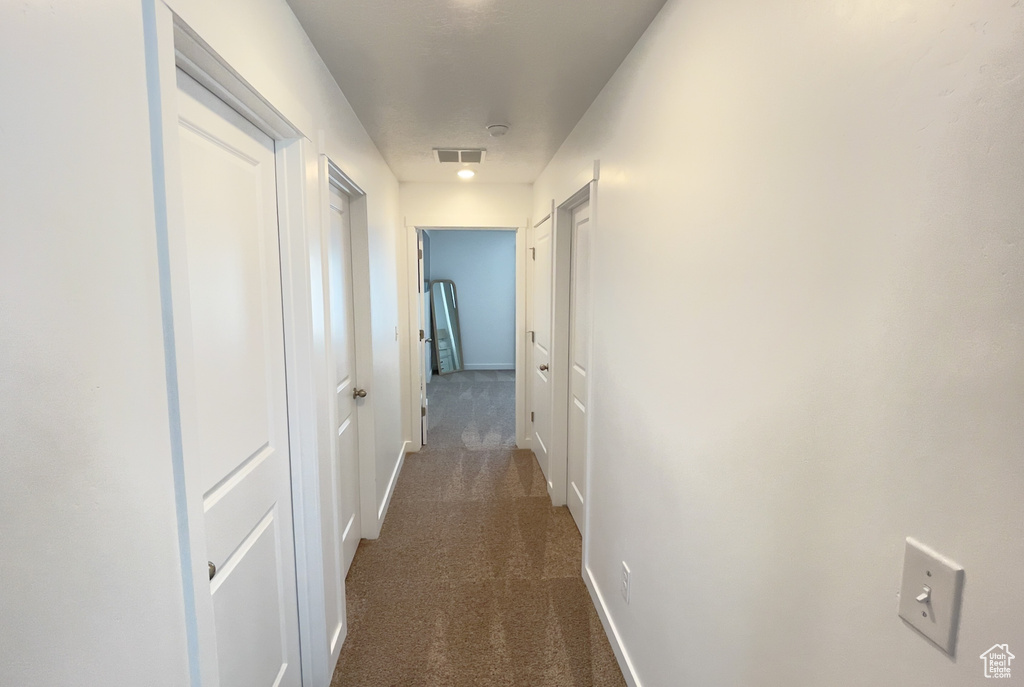 Hall with dark carpet and baseboards
