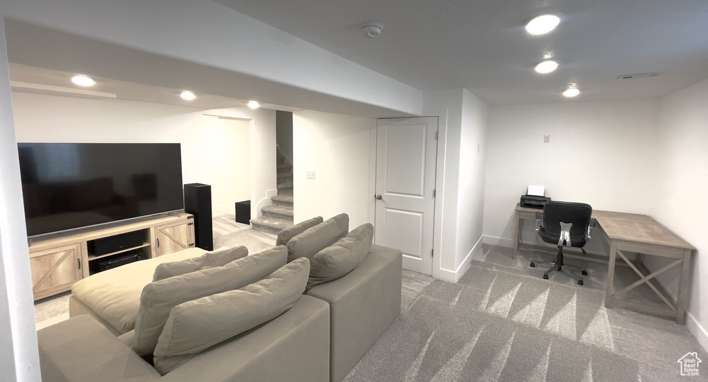 Carpeted living room with baseboards, stairs, and a desk