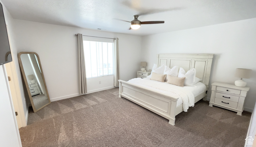 Bedroom featuring dark colored carpet, ceiling fan, and baseboards