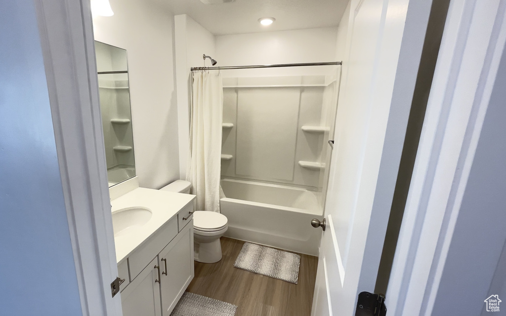 Full bath featuring vanity, wood finished floors, shower / tub combo, and toilet