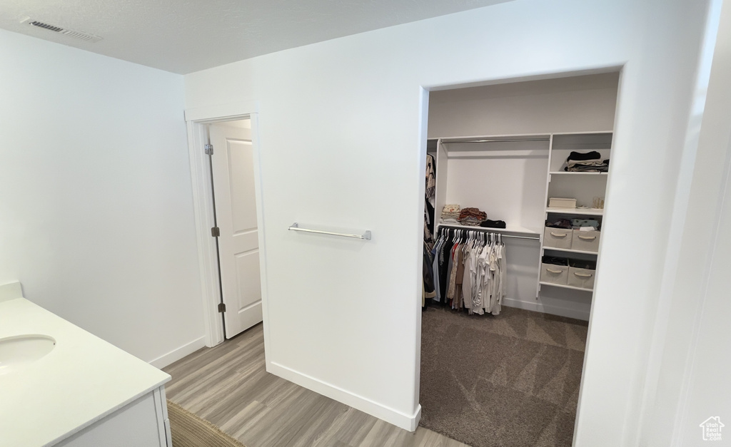Bathroom featuring vanity, a spacious closet, wood finished floors, and baseboards