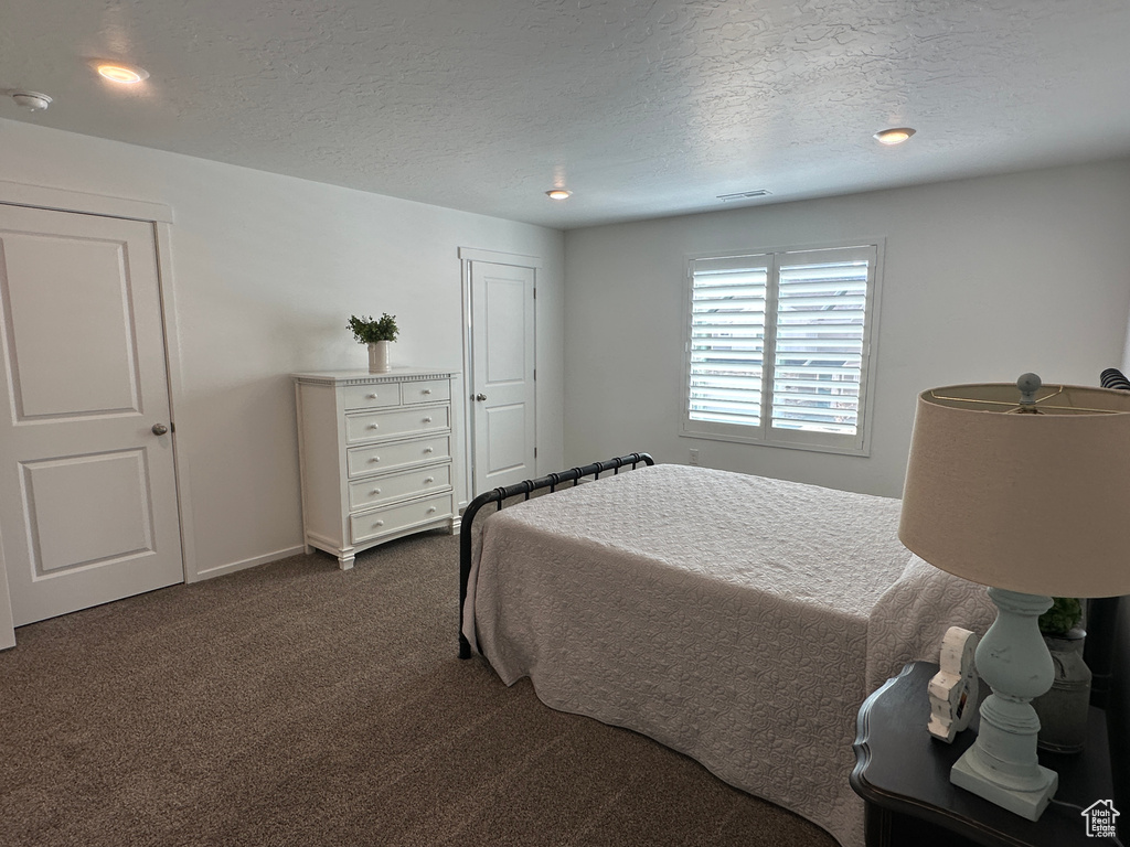 Bedroom featuring dark carpet, a textured ceiling, recessed lighting, and baseboards