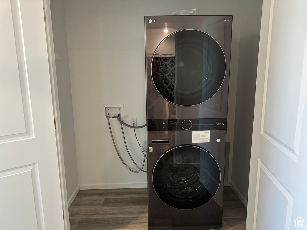 Laundry room featuring estacked washer and dryer, wood finished floors, and baseboards