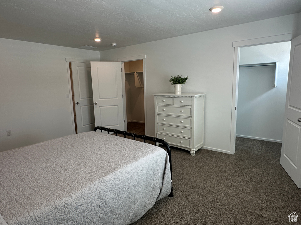 Bedroom featuring a walk in closet, dark colored carpet, a closet, recessed lighting, and baseboards