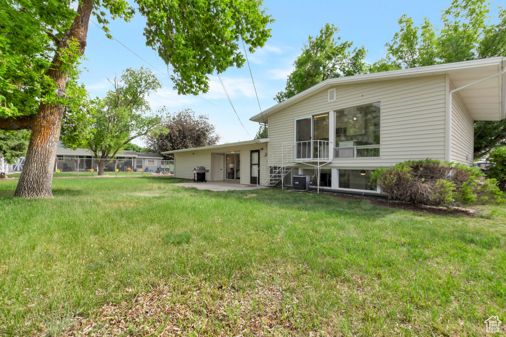 View of grassy yard featuring central AC unit and a patio area