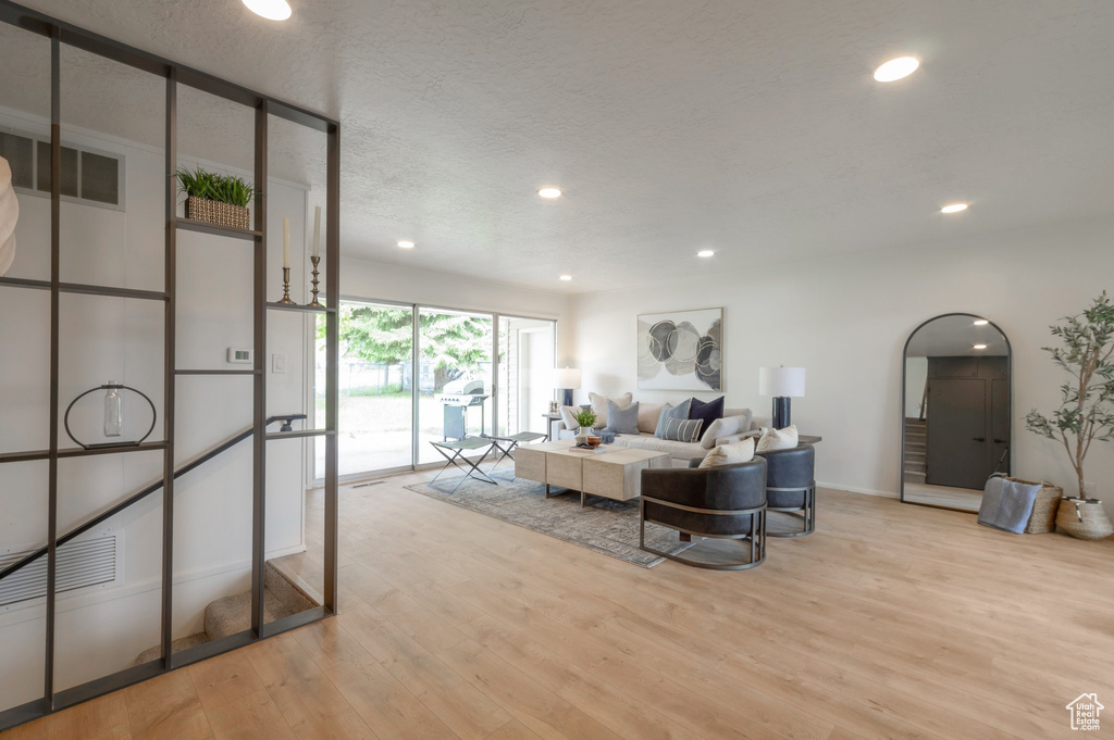 Living room featuring light wood finished floors, recessed lighting, baseboards, and a textured ceiling