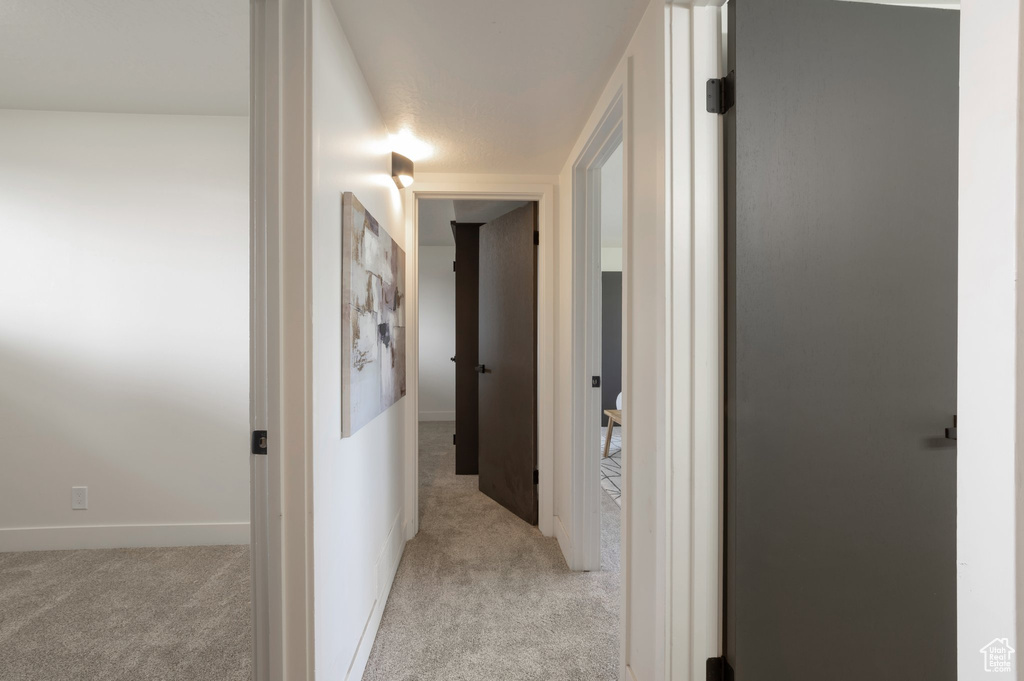 Hallway with light colored carpet and baseboards
