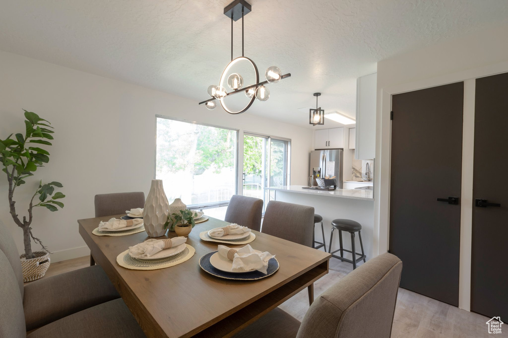 Dining area with a chandelier, light wood-style flooring, and a textured ceiling