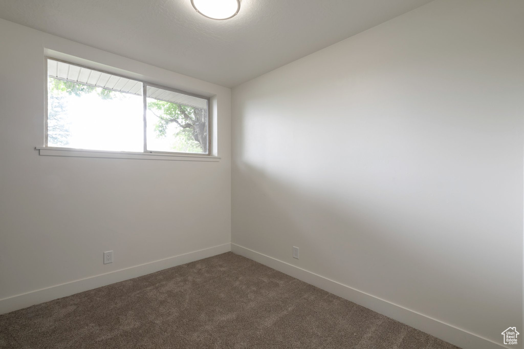 Unfurnished room featuring dark carpet and baseboards