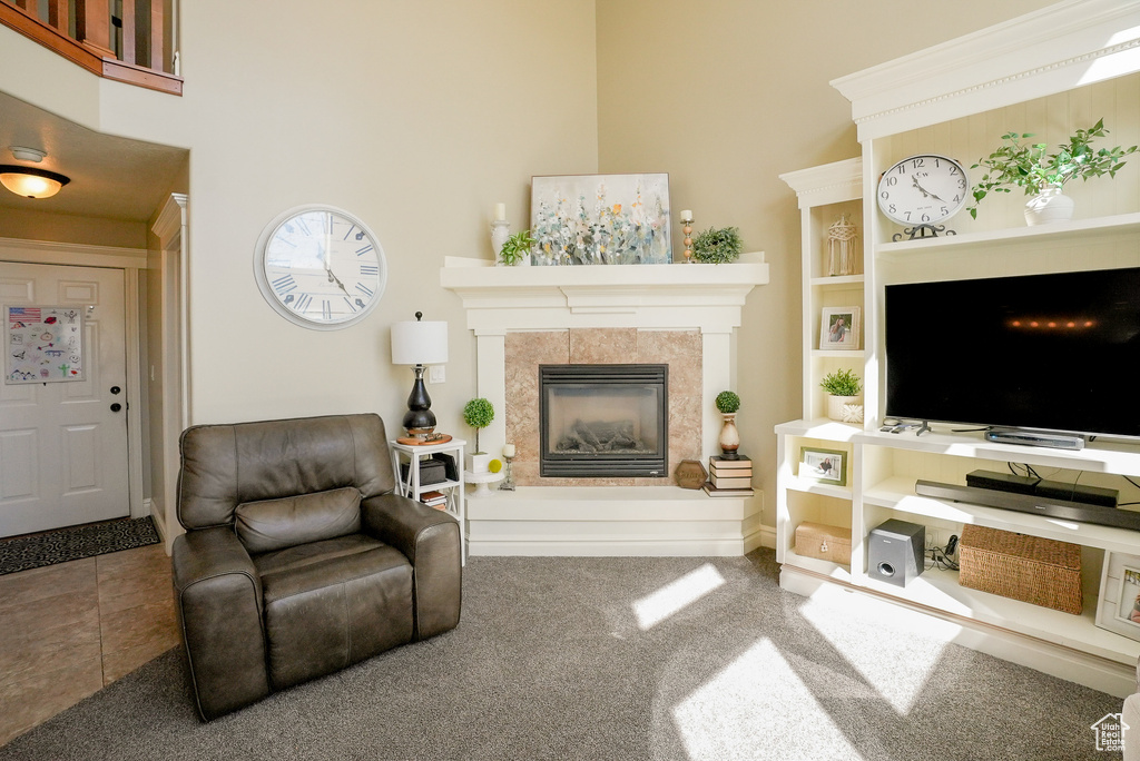 Carpeted living area with a tile fireplace and a high ceiling