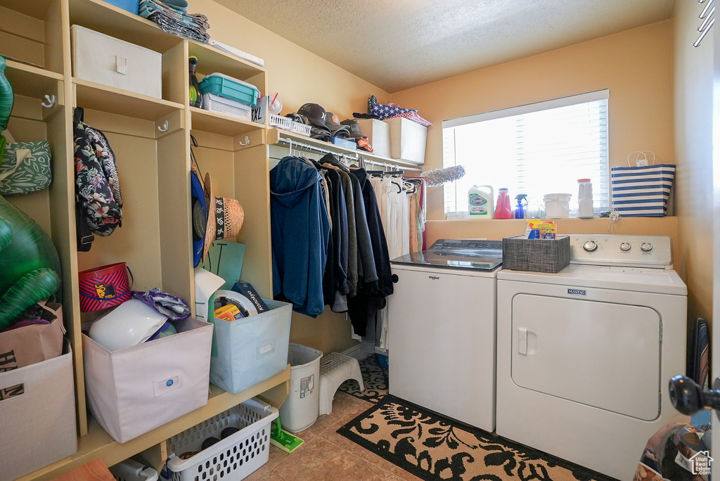 Laundry room with independent washer and dryer, a textured ceiling, and tile patterned flooring