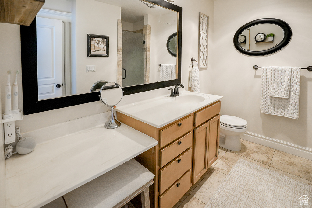 Bathroom featuring toilet, vanity, an enclosed shower, tile patterned floors, and baseboards