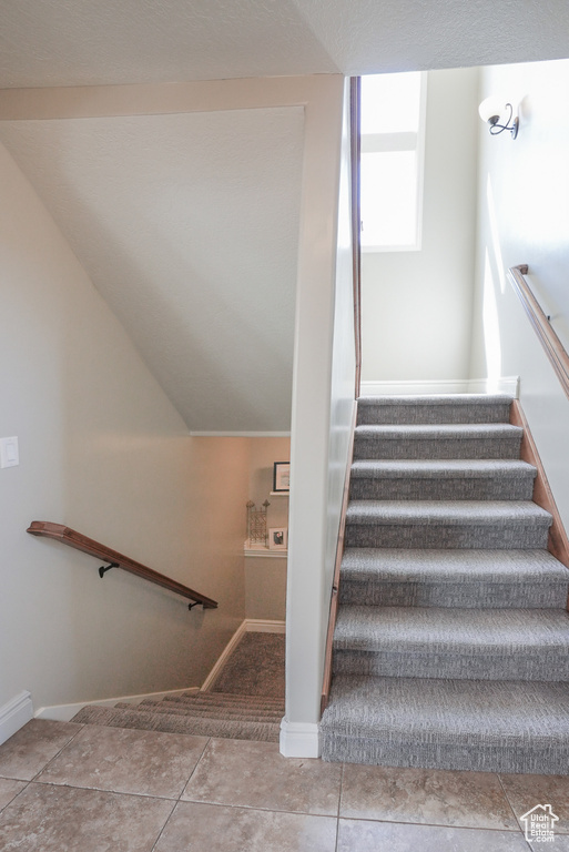 Staircase with baseboards and tile patterned flooring