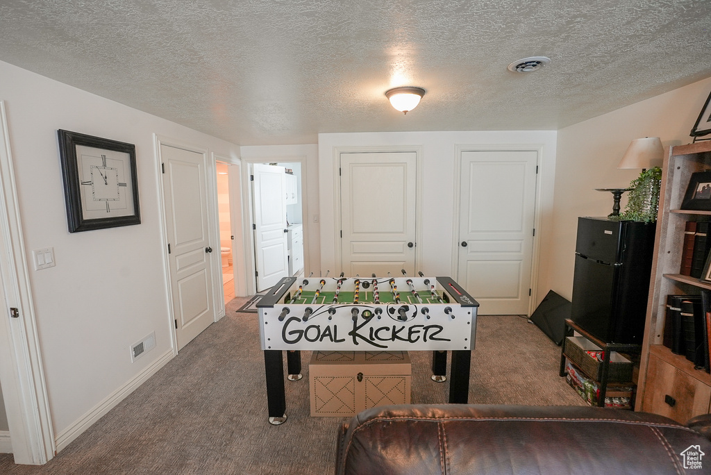 Recreation room featuring carpet floors, a textured ceiling, and baseboards