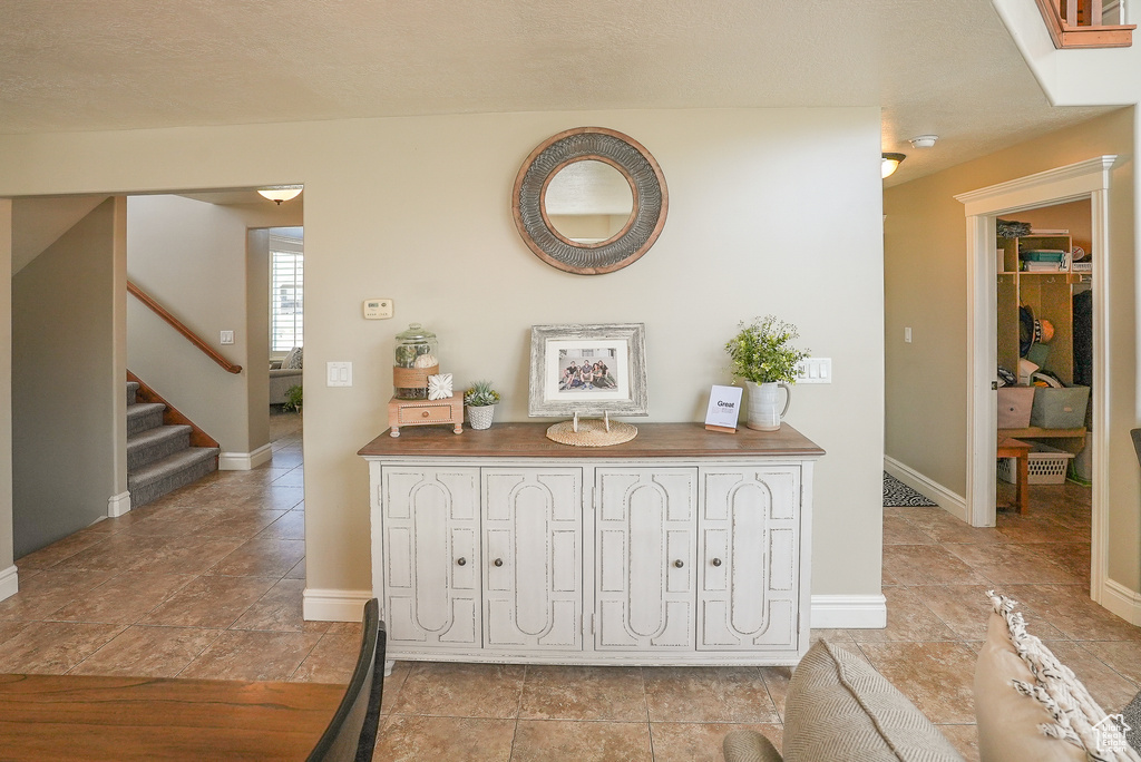 Corridor with stairway, baseboards, and light tile patterned floors