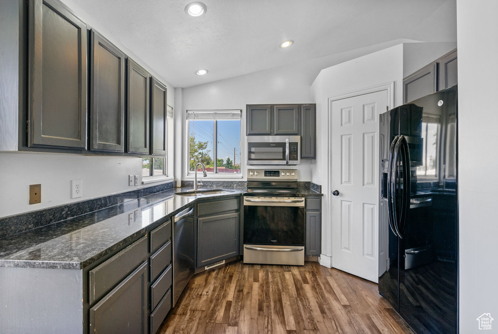 Kitchen with appliances with stainless steel finishes, a sink, dark wood-style flooring, recessed lighting, and gray cabinets