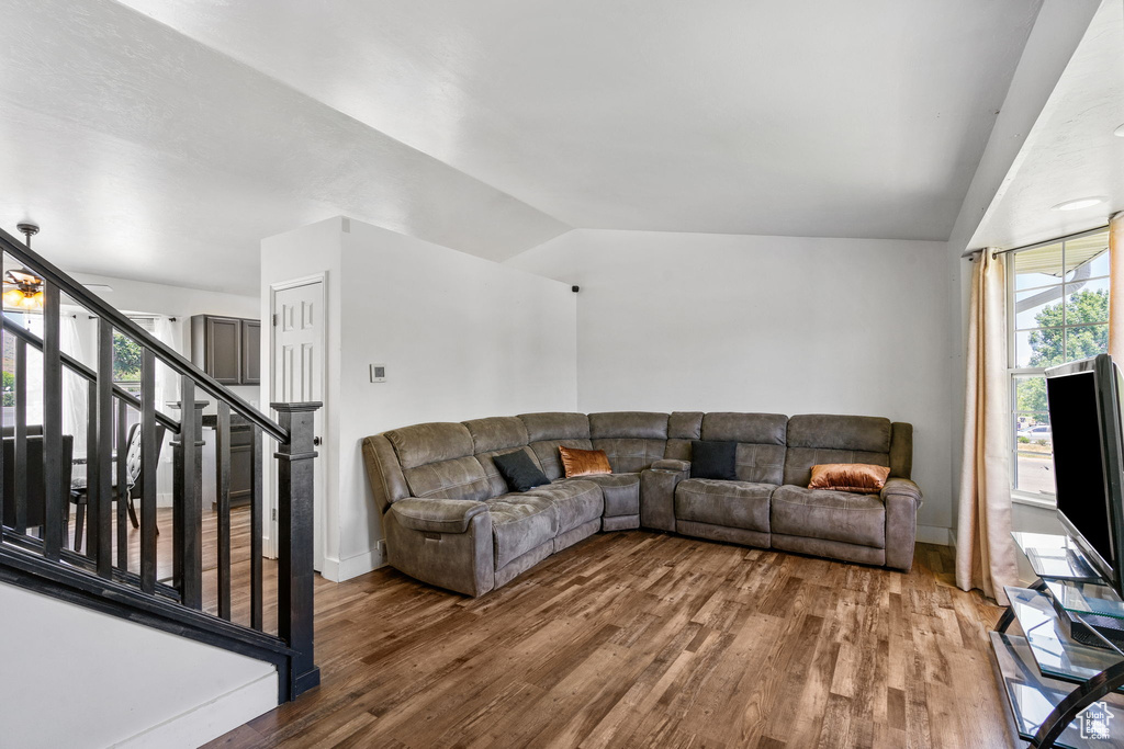 Living area with wood finished floors, lofted ceiling, stairs, and baseboards
