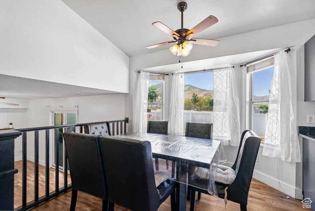 Dining room featuring ceiling fan, healthy amount of natural light, vaulted ceiling, and wood finished floors