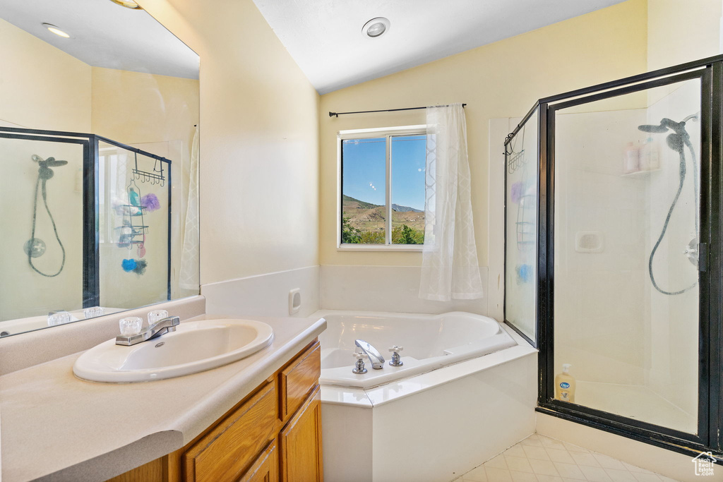 Full bath featuring a stall shower, a bath, vanity, vaulted ceiling, and tile patterned flooring