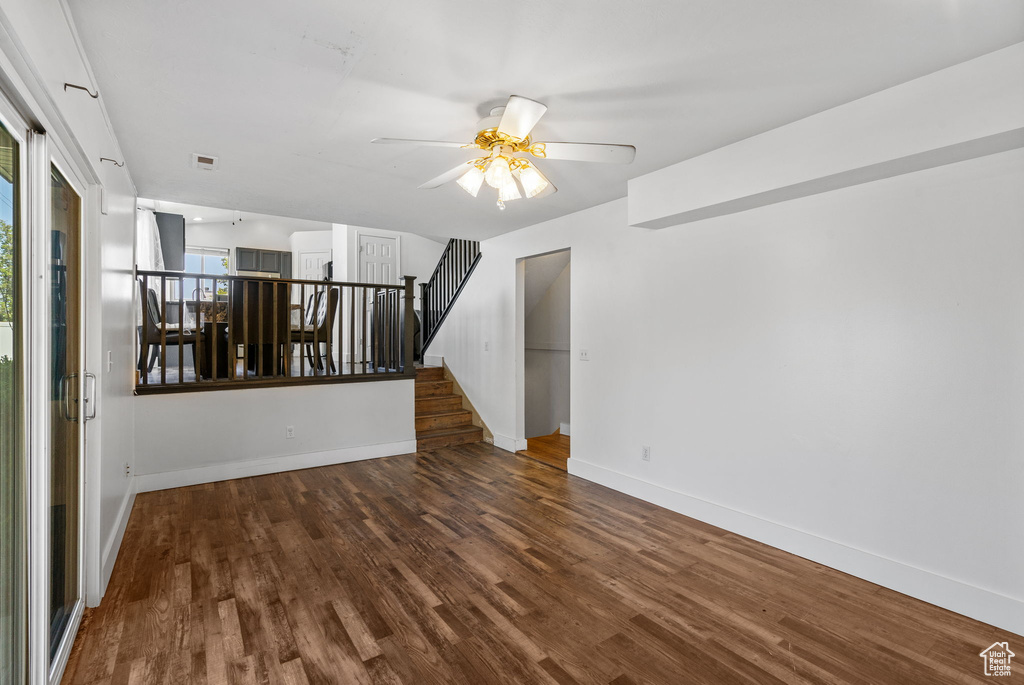 Empty room with wood finished floors, baseboards, a ceiling fan, and stairway